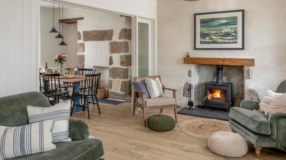Cosy living room at Ealing House featuring sage green sofa and wood burning stove in Porthleven Cornwall
