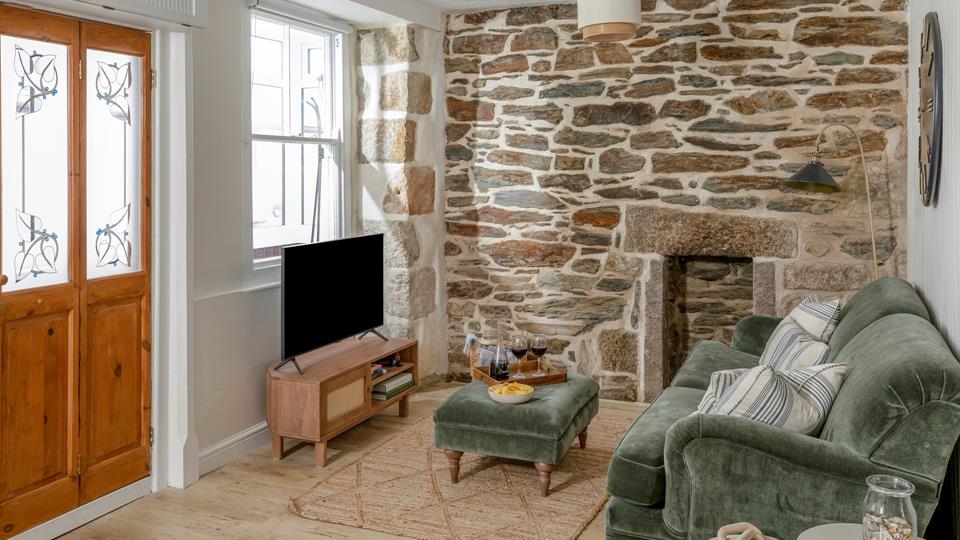 Feature exposed stone wall adding character to living room at Ealing House Cornwall